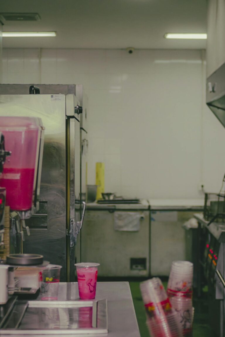 Clean and organized commercial kitchen interior with beverage machines and stainless steel surfaces.