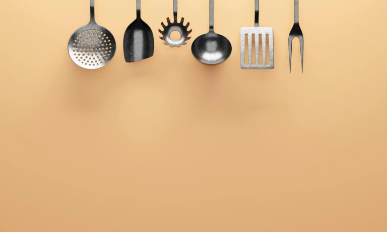 Display of various stainless steel kitchen utensils on an orange background.